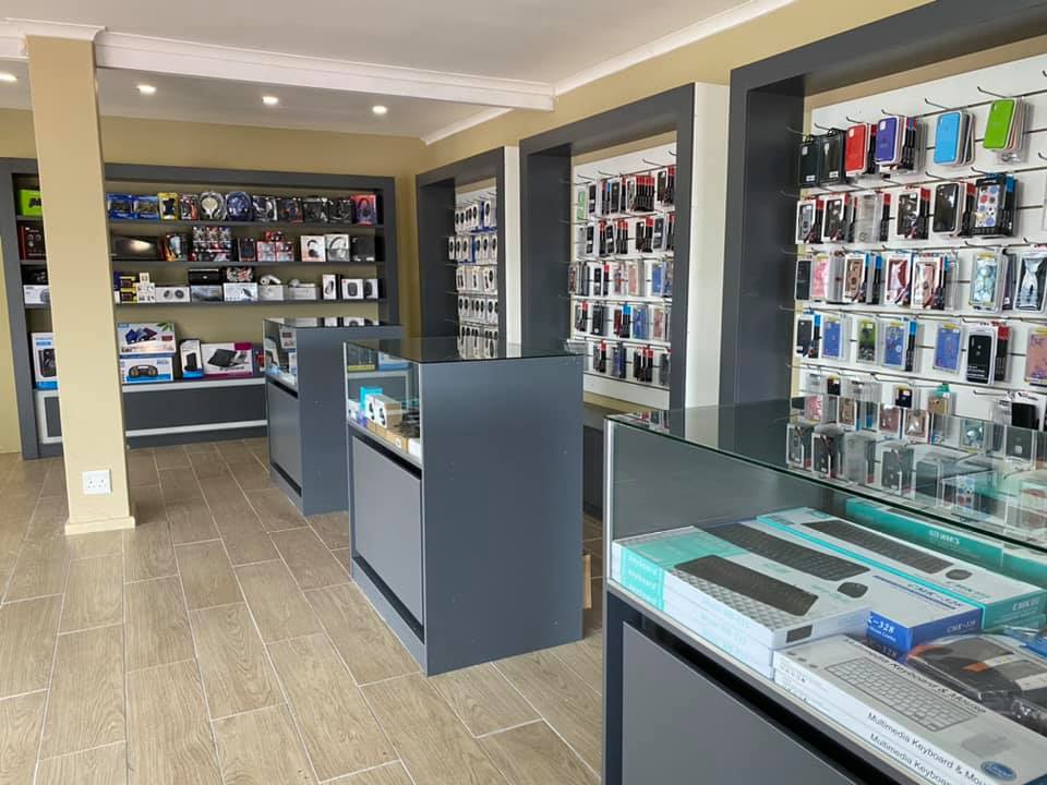 Inside a tech accessory store with several glass display counters and walls lined with phone cases and electronics under warm lighting.